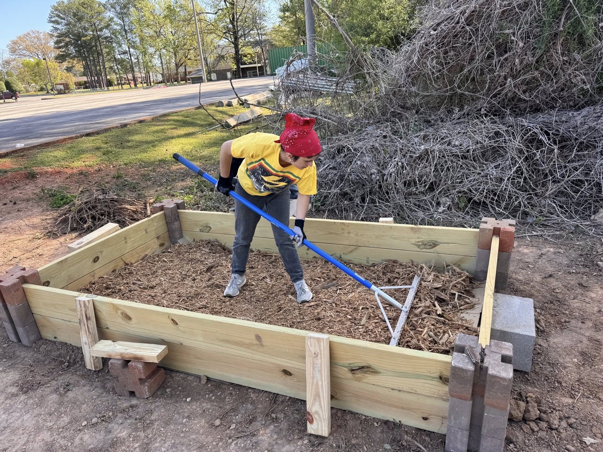 Community member raking soil in raised garden bed