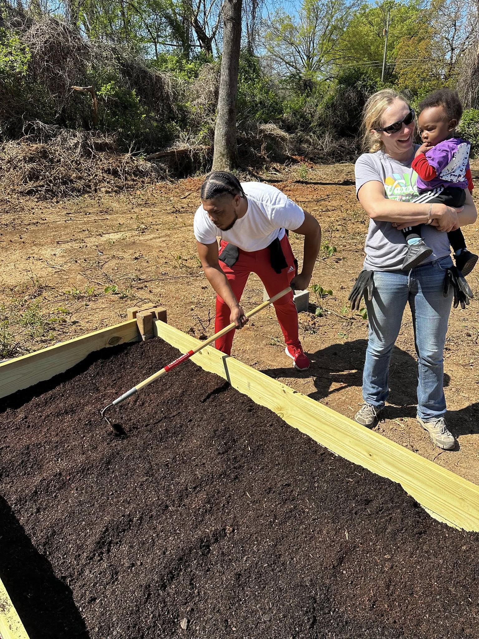 Family working together preparing garden soil with child